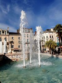 Fountain in swimming pool against buildings in city