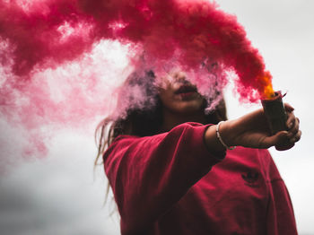 Young woman photographing with pink camera