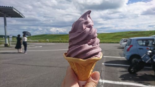 Cropped image of hand holding ice cream on road