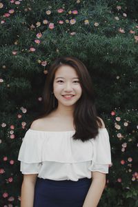 Portrait of young woman standing against tree