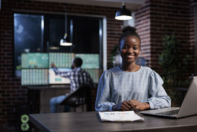 Portrait of smiling businesswoman sitting by desk