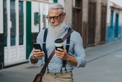 Portrait of young man using mobile phone in city