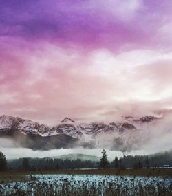 Snow covered landscape against cloudy sky