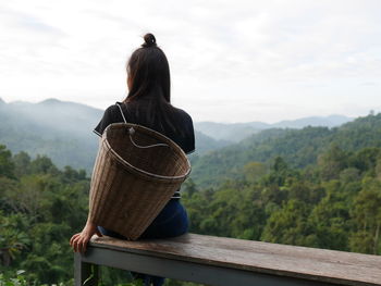 Rear view of woman siting on bench looking at landscape