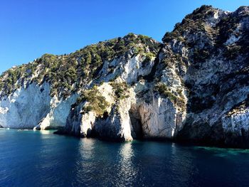 Scenic view of sea and mountains against clear blue sky