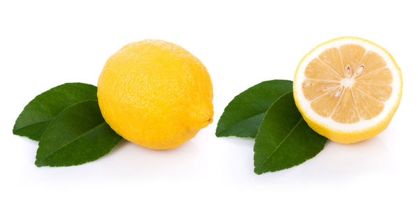 Close-up of lemon with leaves against white background
