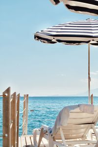 Chairs and table on beach against clear sky