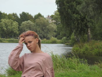 Portrait of girl looking at lake against trees