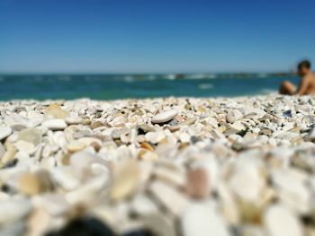 Surface level of pebble beach against clear blue sky