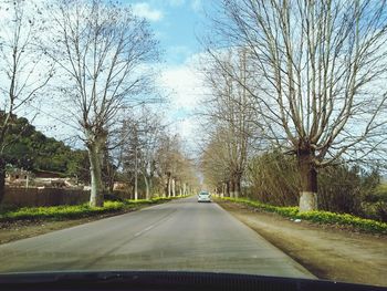 Road amidst bare trees against sky
