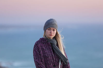 Portrait of young woman standing against sea during winter