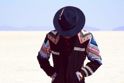 Man looking down wearing hat and costume at salar de uyuni