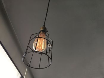 Low angle view of illuminated light bulb hanging from ceiling