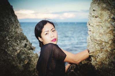 Portrait of woman by rocks at beach