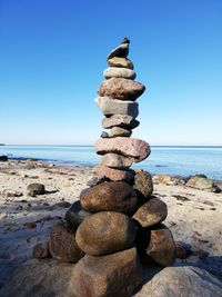 Stack of pebbles on beach against clear sky