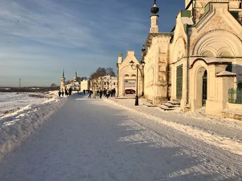 Snow covered buildings in city against sky