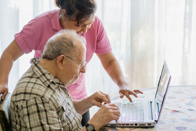 Nurse assisting senior man in typing