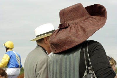 Rear view of man and woman wearing hat against sky