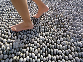 Low section of woman walking on pebbles