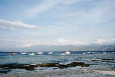 Sailboats moored in sea against sky