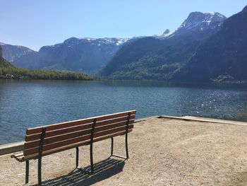 Empty bench by lake against mountains