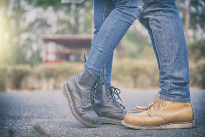 Low section of couple wearing shoes while standing on road