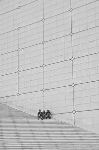 People walking on staircase against wall