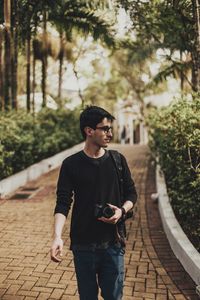 Young man looking away while walking on footpath