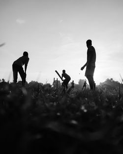 Silhouette people on field against sky