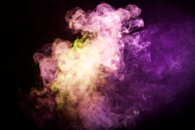 Colorful smoke of orange, pink on a black isolated background. background from the smoke of vape