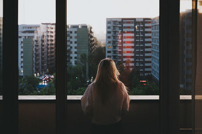 Rear view of woman standing against buildings in city