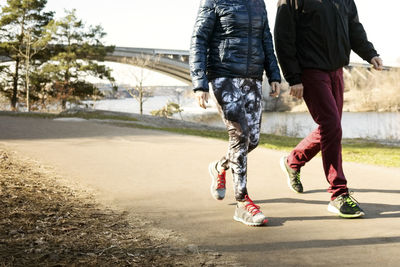 Low section of man and woman in sportswear walking on road