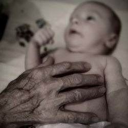 Close-up of shirtless baby holding hand