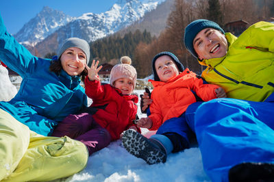 Portrait of happy friends sitting on snow