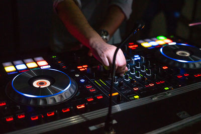 Hands of dj tweak various track controls on dj sound mixer