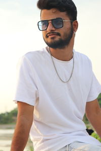 Young man wearing sunglasses standing against sky