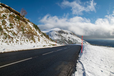 Road amidst snowcapped mountains against sky