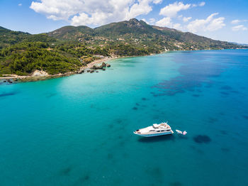 Aerial view of boat in sea against mountains and sky