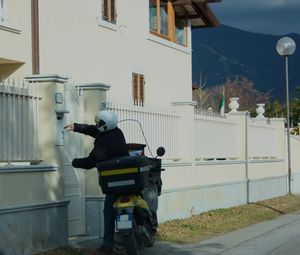 Rear view of man riding motorcycle on street against buildings