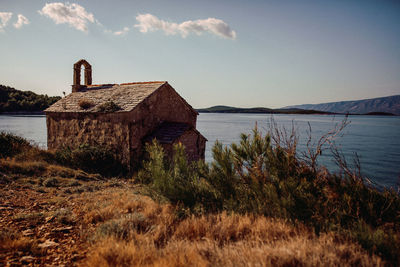 Built structure by lake against sky