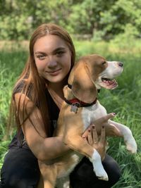 Portrait of woman with dog on grassy field