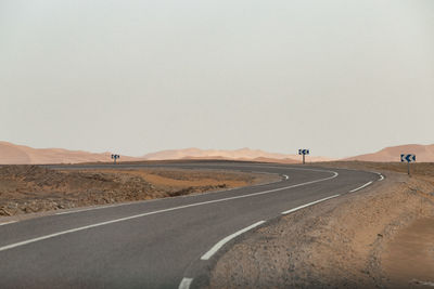 Road by desert against clear sky