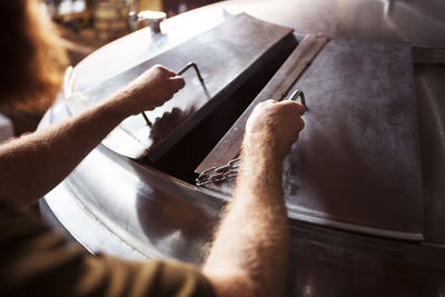 Cropped image of brewer opening machinery at brewery