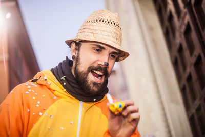 Close-up of cheerful man in hat standing outdoors