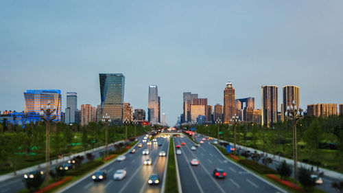 Traffic on highway by buildings in city against sky