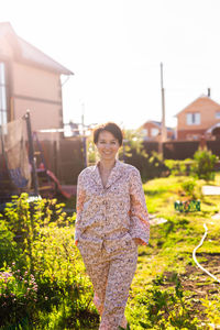 Portrait of young woman standing against building