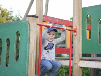 Smiling boy crouching on jungle gym in playground