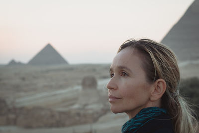 Woman looking away against pyramids and sky