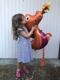 Full length of cute girl holding balloon standing outdoors