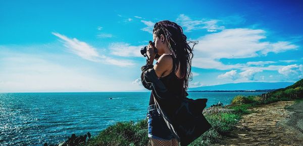 Woman photographing sea from camera